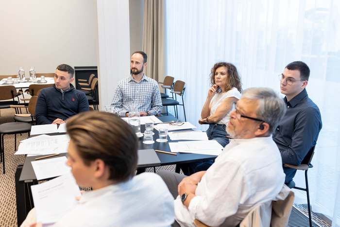 Uczestnicy w trakcie rozmowy, jedna osoba mówi do pozostałych.